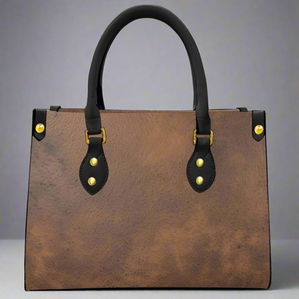Brown leather imprinted faux leather bag with rolled black handles and imprint of cowgirls on each end of bag.