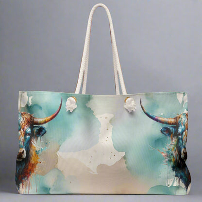 Colorful imprint of watercolor background with steer heads on the ends of the bag. Large overnight style tote bag with white rope handles. 