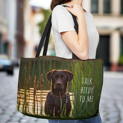 Large weekender style canvas tote bag imprinted both sides with our exclusive image of an intense chocolate Labrador Retriever duck hunting dog waiting near the reeds and cattails.  It reads TALK BIRDY TOME. Imprinted the same n both sides. Woven cotton handles.