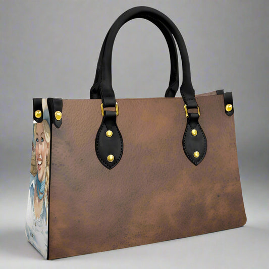 Brown leather imprinted faux leather bag with rolled black handles and imprint of cowgirls on each end of bag. 