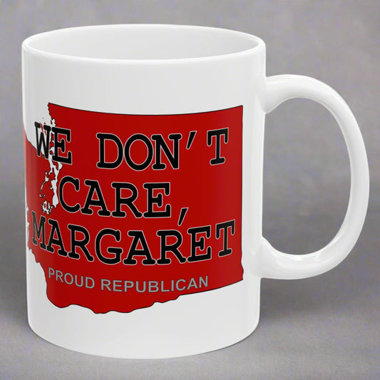 White 11 oz. ceramic coffee mug imprinted on both sides with a red shape of Washington state. Over the top of the image is WE DON'T CARE, MARGARET and Proud Republican. Mug made from an imported base and printed in USA.