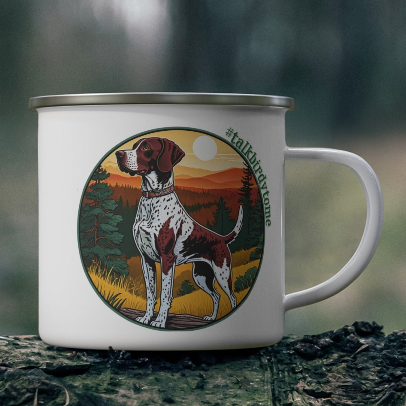 Enamel mug with imprint of German shorthaired pointer ready to go to work.  Shows dog at the ready and waiting to retrieve a bird. Pretty sunrise over distant mountains with golden grasses and green pine trees. Encircled with the tag line #talkbirdytome. White enamel coated stainless steel camping coffee mug. Same imprint on both sides.