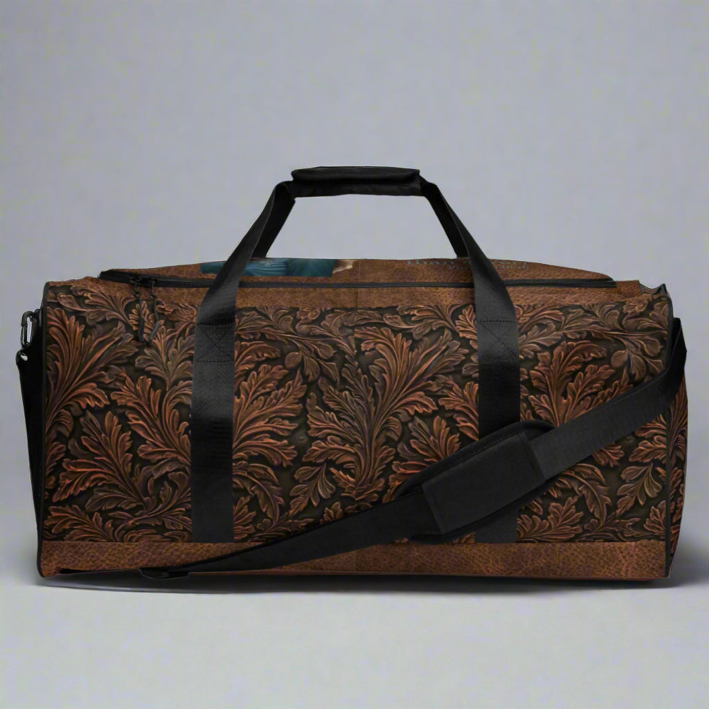 All-over print western tooled leather imprint duffle bag. Black carry straps and handles. Mesh exterior pocket. Imprinted with pretty cowgirl and Proverb about wisdom and good judgment being more valuable that silver and gold. 