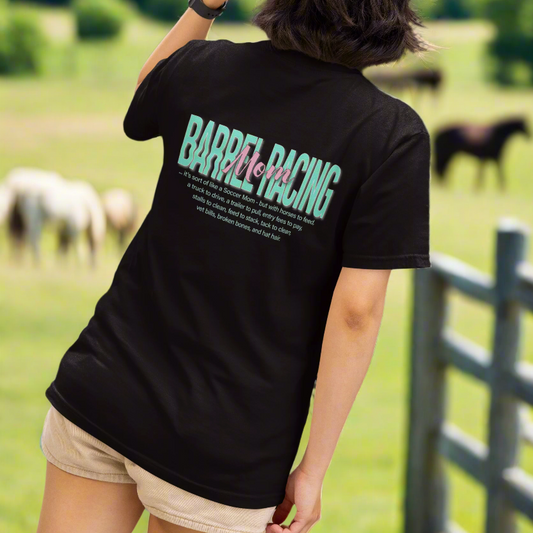 Woman in short sleeve t-shirt imprinted with Barrel Racing Mom on the back. Front has the Barnburner Apparel bovine logo on the left front chest. 