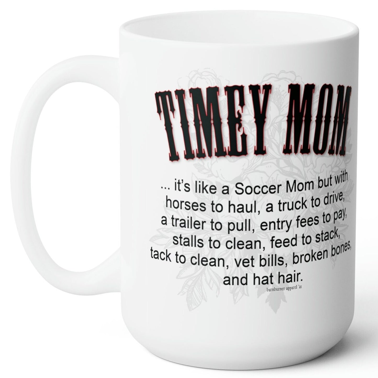 A white ceramic mug sitting on a wood picnic table. Imprint on both sides of the mug reads the same: TIMEY MOM... it's like a Soccer Mom but with horses to haul, a truck to drive, a trailer to pull, entry fees to pay, stalls to clean, feed to stack, tack to clean, vet bills, broken bones, and hat hair.