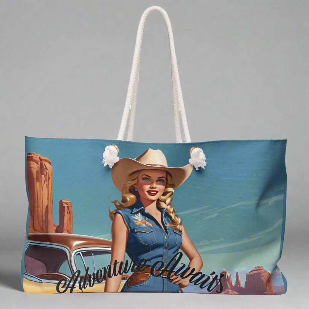 Pretty retro cowgirl in a cowboy  hat and denim standing in front of  her vintage car beneath a blue sky with a southwestern US landscape behind her. Ready to hit the road! The weekender bag has white twisted rope handles and an off-white sheeting lining. Perfect for overnight and road trips!