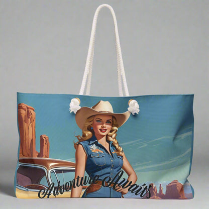 Pretty retro cowgirl in a cowboy  hat and denim standing in front of  her vintage car beneath a blue sky with a southwestern US landscape behind her. Ready to hit the road! The weekender bag has white twisted rope handles and an off-white sheeting lining. Perfect for overnight and road trips!