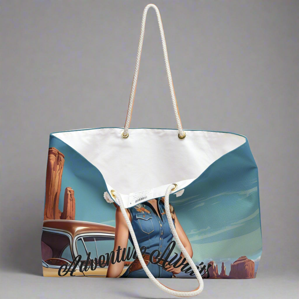 Pretty retro cowgirl in a cowboy  hat and denim standing in front of  her vintage car beneath a blue sky with a southwestern US landscape behind her. Ready to hit the road! The weekender bag has white twisted rope handles and an off-white sheeting lining. Perfect for overnight and road trips!